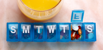 Prescription Plan - Glass of juice next to a weekly pill box